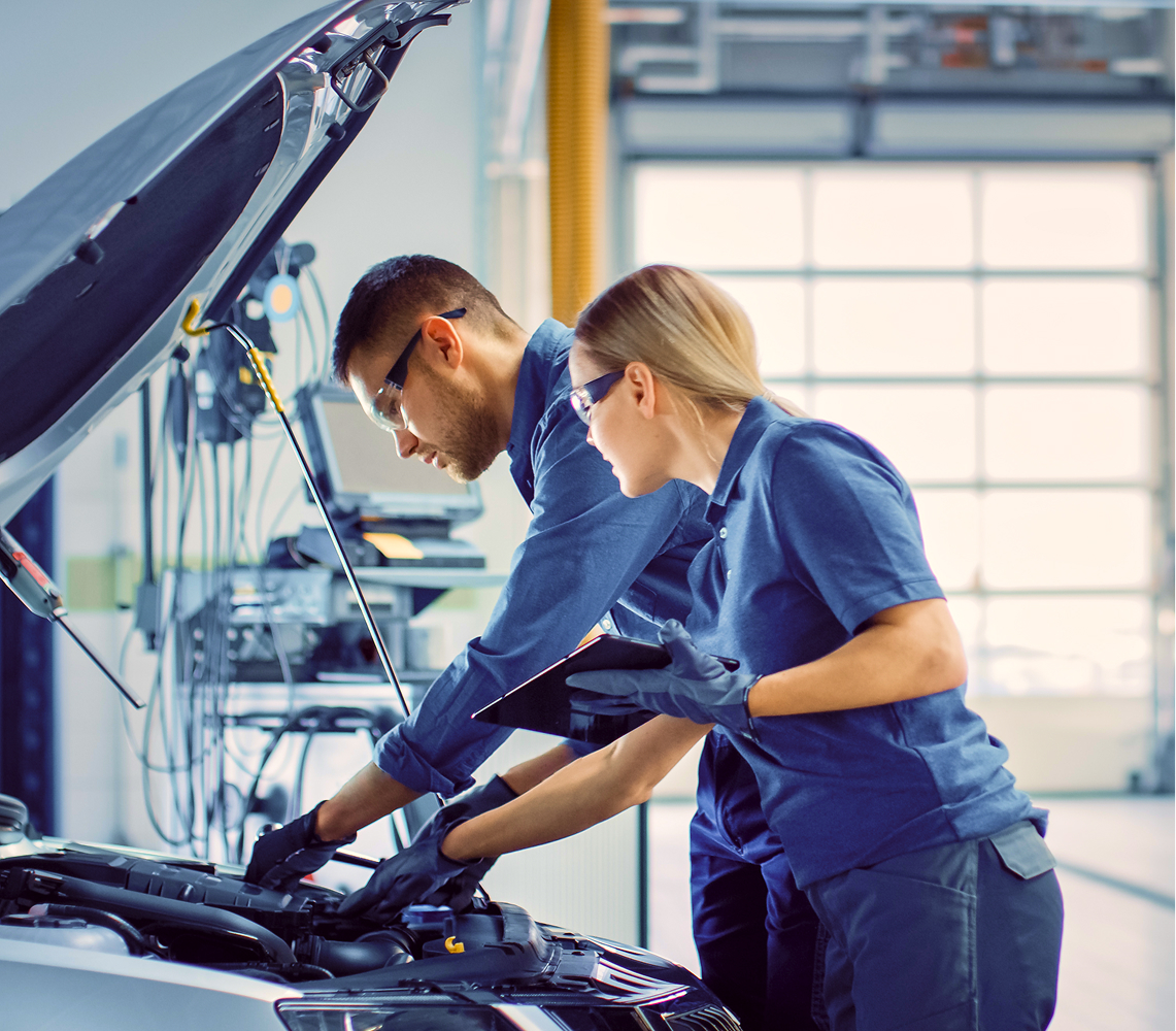 Two people working on a car. 